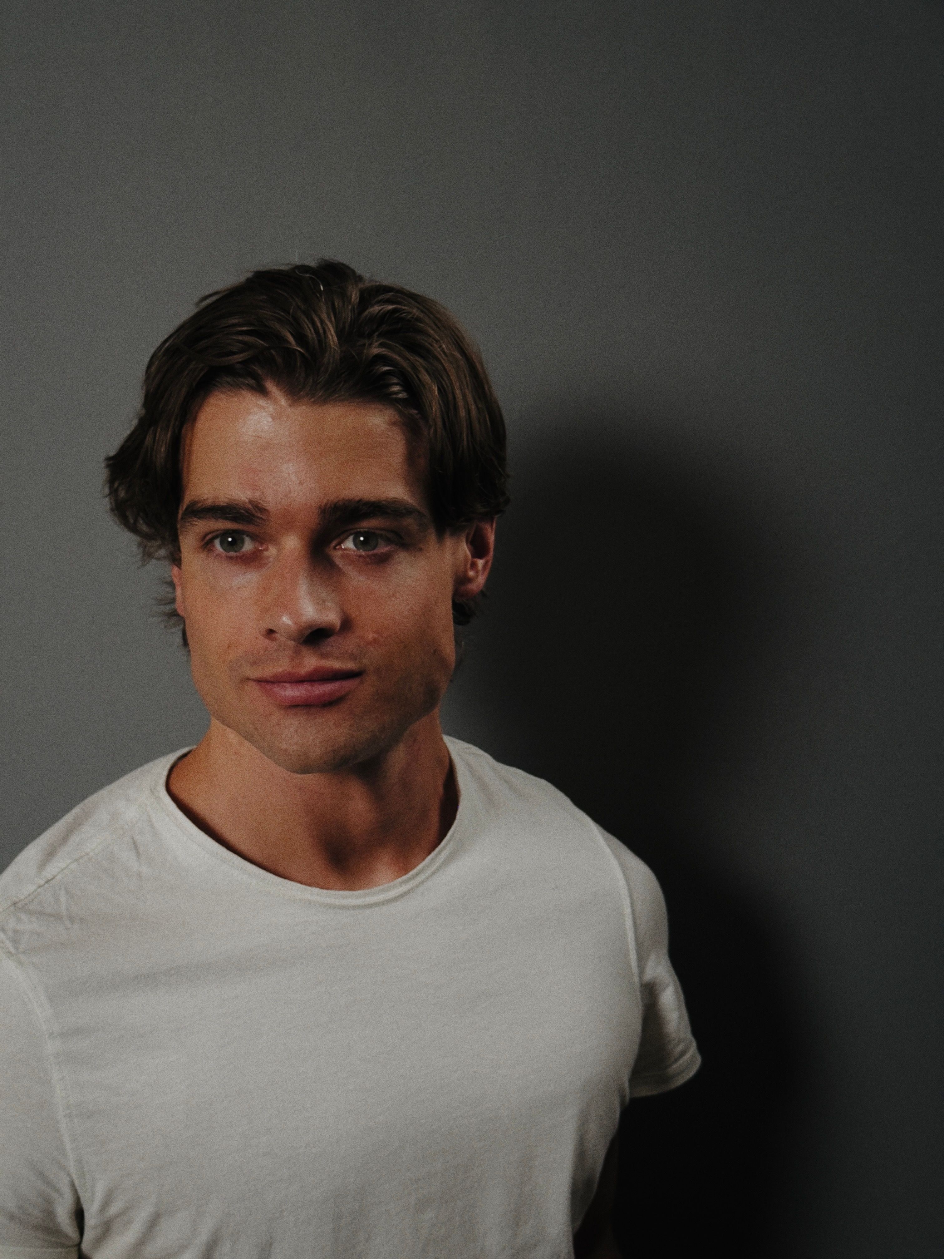 Portrait of Austin Falk in a white T-shirt against a gray wall